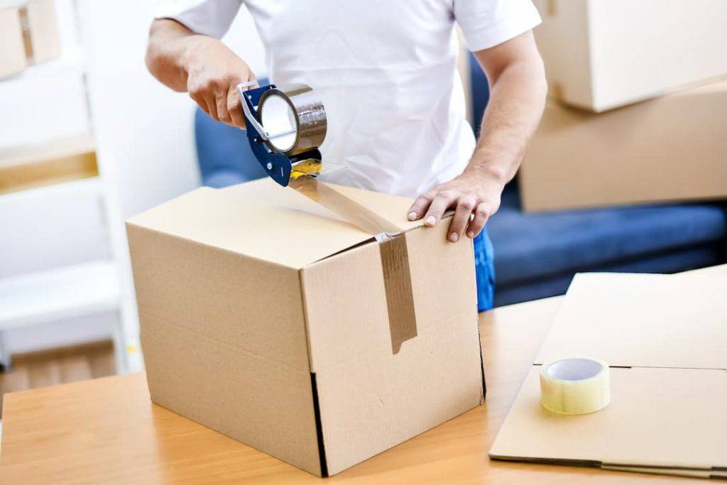 Worker Hands Holding Packing Machine And Sealing Cardboard Or Paper Boxes